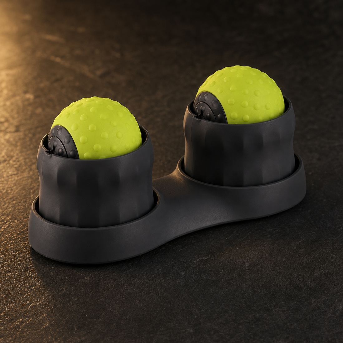 AuraZen TheraSphere double massage-ball device in charcoal and green on a dark studio surface.